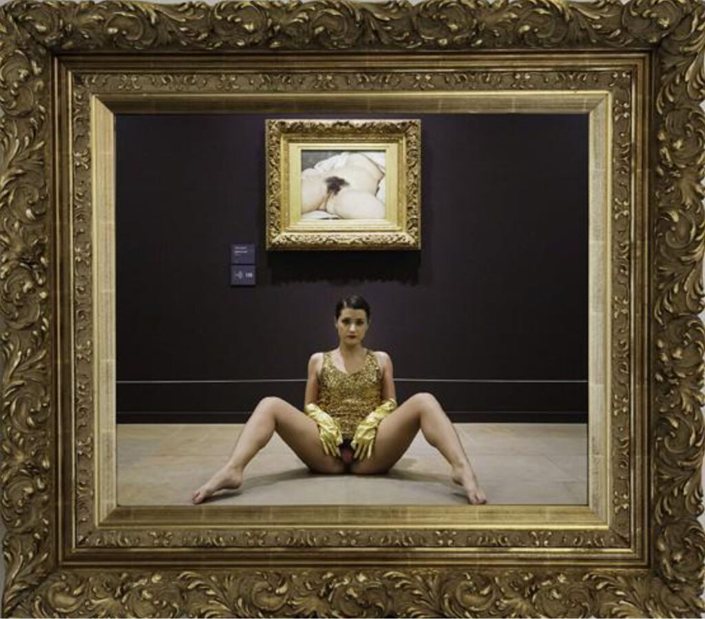 Femme jambes écartées devant la peinture L'Origine du Monde